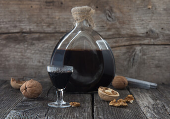 Homemade tincture of walnuts on a wooden background.