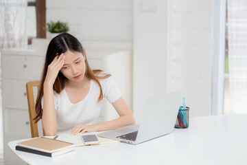 Young asian woman headache during working on laptop computer with deadline on desk at home, business woman with failure exhausted and tired, stress and worried, frustrated and unsuccessful.