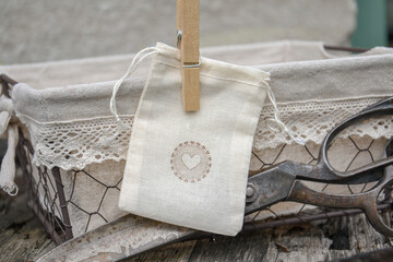 Cotton muslin bag with heart stamp design, with wooden peg holding it on the basket. Antique...