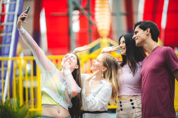 Group of happy best friends laughing and taking selfie photo at amusement park, holiday travel with friends concept