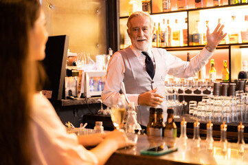 Expert barman is making cocktail at night club, senior bartender working at bar counter