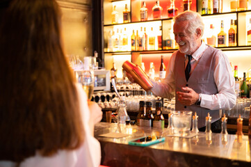 Expert barman is making cocktail at night club, senior bartender working at bar counter