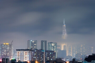 Obraz premium Spectacular view of a landmark 81 skyscraper in mist and clouds at Saigon at night in Ho chi minh city, Vietnam