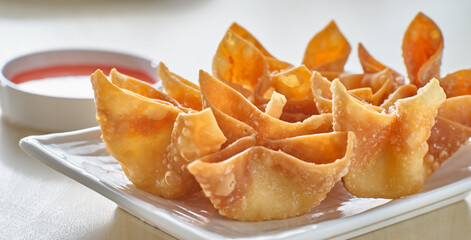 chinese crab rangoon fried wontons on plate with red sauce