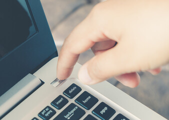 Finger pushing start power button on the laptop computer. Press turn off shutdown keyboard on...