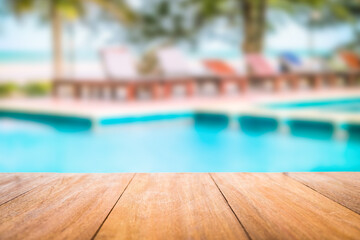 Image of wood table in front of a swimming pool blurred background. Brown wooden desk empty counter...
