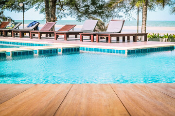 Image of wood table in front of a swimming pool background. Brown wooden desk empty counter in...