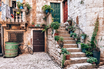 Picturesque street in Trogir city with flower pots and fresh laundry