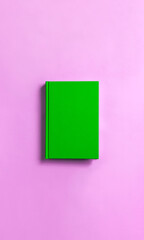 green book on pink background.   ピンク背景の上の緑色の本