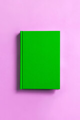 green book on pink background.   ピンク背景の上の緑色の本