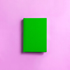 green book on pink background.   ピンク背景の上の緑色の本