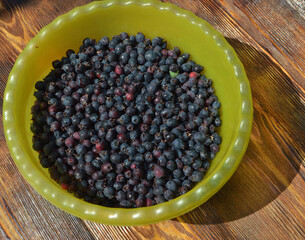 
fresh berry irga lies in a container on a wooden table