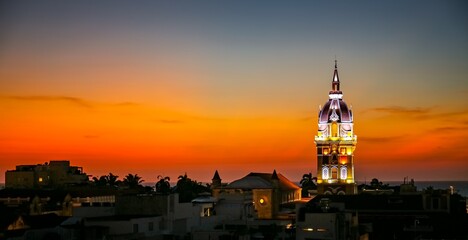Wonderful panoramic view after sunset over Cartagena with illuminated Cartagena Cathedral against orange-yellow sky
