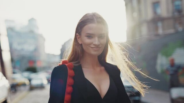 Shot back gorgeous young woman walking turns to camera smiling at sunlight on street city pretty lady fashion model natural sexy close up slow motion