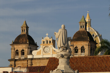 Fototapeta na wymiar Close up view over roofs in Cartagena with statue and bell towers of church San Pedro Claver 