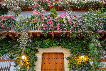 Fototapeta na wymiar Low angel view to a house entrance and with flowers decorated balconies, Colombia, Unesco World Heritage 