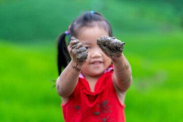 Girl playing outdoor showing dirty muddy hands. Happy childhood