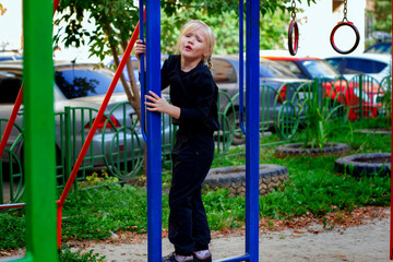 Adorable blond toddler girl with pigtails playing on the playground on the warm day