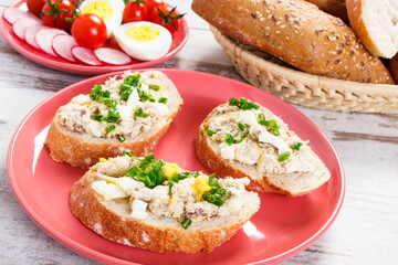 Slice of baguette with fish paste, egg, tomato, radish and fresh rolls