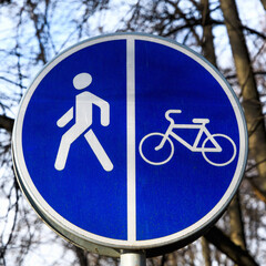 Round blue sign "Pedestrian and Bicycle path" close-up. A sign that divides the path for pedestrians and bicyclists.