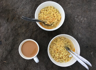 two bowls of instant noodles and coffee milk on the table