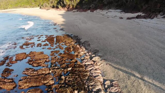 Man Walking On The Sand At The Monro Beach Walk In The West Coast Of New Zealand On A Late Afternoon - descending drone shot