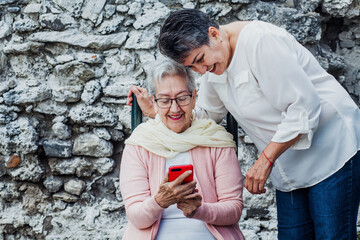 mexican elderly mother and adult daugther woman in Mexico Latin America with smartphone
