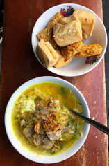Soto Daging with side dishes of tofu and tempeh. Indonesian food
