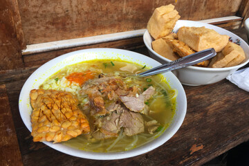 Soto Daging with side dishes of tofu and tempeh. Indonesian food