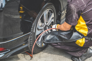 Cropped shot of mechanic pumping up car tire. Inflating the tyre. - obrazy, fototapety, plakaty