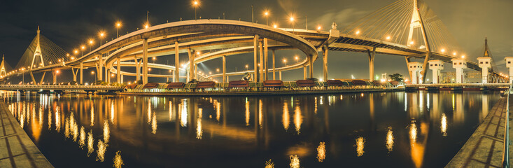 The beautiful panorama view floodgate of Bhumibol Bridge during the night time in Bangkok at Thailand, known as the Industrial Ring Road Bridge over the Chao Phraya River.