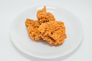 Hot fried chicken wing spicy in plate on white background. Delicious southern Kentucky drumstick crunchy meal. Recipe fast food pieces.