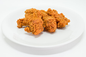 Hot fried chicken leg spicy in plate on white background. Delicious southern Kentucky drumstick crunchy meal. Recipe fast food pieces.