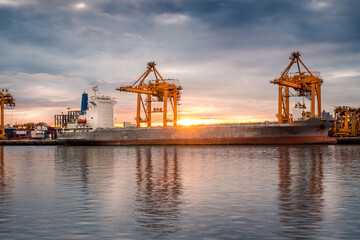 Harbor with anchored ship. Container cargo freight ship with working crane bridge at a shipyard in for logistic transportation import and export at Asia haven port background, Samutprakarn, Thailand.