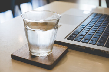 Glass of water cold on the table with laptop computer working business in the office background.