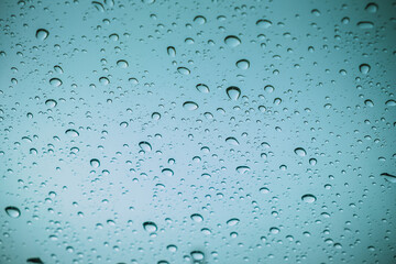 Blue drops of rain on a window glass in the city. Image of raindrops texture background.