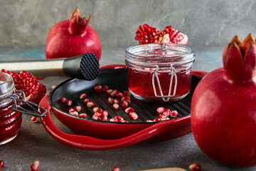 Homemade sweet red pomegranate syrup in jars of pomegranate seeds on a black plate with a red rim