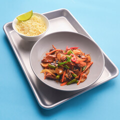 Fresh rice and chicken in gravy sauce with tomatoes, red pepper and green beans served in seperate plates on metal tray.