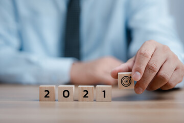 Hand holding wood cubes with New year 2021 and goal or target icon. concept of New year Business goals and vision.