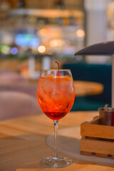 A glass with the red citrus cocktail. Alcohol summer beverage in a wine glass. Refreshing drink with ice.