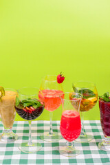 Summer drinks with fruit juice and ice. Refreshing summer beverages in different glasses over green background.