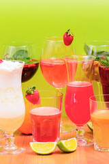 Summer drinks with fruit juice and ice. Refreshing summer beverages in different glasses over green background.