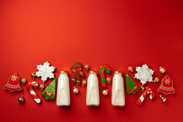 Glass milk bottle and Christmas gingerbread cookies on red background