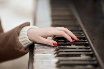 Fototapeta premium Close-up of a manicured hand playing the piano. Red varnish