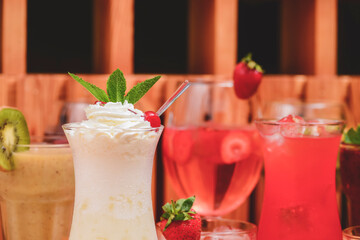 Summer drinks with fruit juice and ice. Refreshing summer beverages in different glasses over rustic wooden background