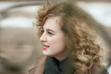 Close-up portrait of curly young woman framed by decorative lattice, red lipstick