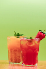 Summer drinks with fruit juice and ice. Refreshing summer beverages in different glasses over green background.