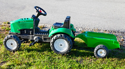 Umea, Norrland Sweden - August 16, 2020: green plastic toy tractor with small trailer