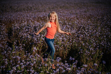glückliches Kind, blondes Mädchen läuft und springt auf dem violetten Blumenfeld. Wiederverbindung mit der Natur.
