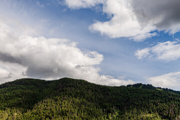 Sky with white clouds above small mountains in british columbia Canada.